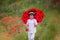 Preschool child in a poppy field with red ladybird umbrella, springtime