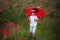 Preschool child in a poppy field with red ladybird umbrella, springtime