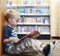 Preschool child reading a book at the library