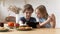 Preschool children seated at table in kitchen using tablet computer