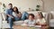 Preschool diverse children drawing with pencils, parents relaxing on sofa