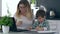 Preschool education, mother helps son to paint with colored felt-tip pens image sitting in kitchen