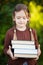 Preschool girl holding pile of books and smiling