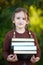 Preschool girl holding pile of books and smiling