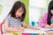 Preschool girl kid drawing with color pencil on white paper on t