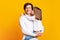 Preschool girl kissing smiling father over yellow background