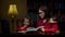 Preschool girl making homework with young 30s mother at home. Cute little girl looking at textbook and writing down in