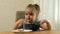 Preschool girl sitting at a table eats soup. Close-up