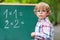 Preschool kid boy with glasses at blackboard practicing mathematics