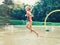 preschool kid child girl running jumping splashing with water of sprinkler at playground during summer hot day