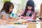 Preschool kids drawing with color pencil on white paper on table