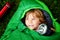 Preschool little girl in sleeping bag camping. Outdoors activity with children in summer. Fun and adventure camp, family