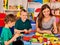 Preschool scissors in kids hands cutting paper with teacher in class.