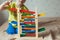 Preschooler baby learns to count. Cute child playing with abacus toy. Little boy having fun indoors at home, kindergarten or day c