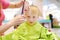 Preschooler boy getting haircut. Children hairdresser with professional tools - comb and scissors