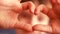 Preschooler boy shows a love heart gesture with his hands. The theme I love you. Child looks through the shape of a heart shown by