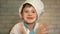 A preschooler Caucasian chef boy in a hat shakes off the flour from his hands. The kid in the kitchen jokingly helps to cook. Youn