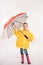 preschooler child in rubber boots, yellow raincoat with umbrella,