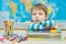 Preschooler child sits at the table,put his hands and head on the books.Learning fatigue, boredom.The boy looks at the camera,does