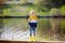 Preschooler child wearing yellow rain boots walking near river after rain. Kid playing and having fun in sunny spring or summer