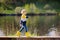 Preschooler child wearing yellow rain boots walking near river after rain. Kid playing and having fun in sunny spring or summer