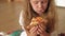 Preschooler girl eating pizza while sitting on floor in room