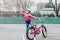 Preschooler girl riding pink bike bicycle in helmet on backyard road outside on spring autumn day