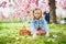 Preschooler girl wearing bunny ears playing egg hunt on Easter