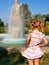 Preschooler little girl watching fountain rear view. Young female child enjoy being outside in summertime. Curiosity blonde