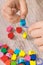 Preschooler making bracelet from thread and colored beads. Development of kids motor skills, coordination and logical thinking