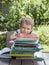 Preschooler sits at table, in front of him is large pile of children`s books