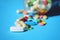 Prescription pills. Multicolor tablets and pills capsules from glass bottle on blue background with Copy space. Heap of assorted