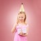Present, birthday hat and child open gift box for holiday party or happy celebration. Excited girl on a pink background