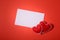 Present box with felt love hearts and greeting card on red paper background. Valentine`s day celebration concept. Top view. Flat