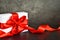 Present box with red ribbon on grey background