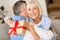 Present of love. Senior woman making surprise for husband