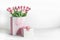 Present setting with pink tulips in shopping bag and gift box at white background. Celebrating in springtime with beautiful