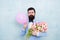 Present for spouse. Guy with air balloon. Birthday party. Bearded man hipster with flower bouquet. 8 march. Flowers for