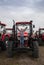 Presentation and sale of new red tractors standing in a row. The child happily stands on a farm tractor