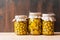 Preserved fermented olives and artichokes in olive oil in glass jars on dark wooden background Autumn vegetables canning