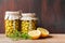 Preserved fermented olives in glass jars with wild fennel and lemon cut on dark wooden background. vegetables canning.