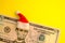 President Lincoln in a red Santa Claus hat on a five-dollar US bill on a bright yellow background. The concept of the cost of