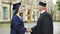 Presiding officer giving diploma to female student, shaking hand, convocation