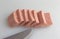 Pressed pork canned meat chunks on a cutting board with knife.