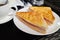 Pressed and toasted double panini with ham and cheese served on white plate with a cup of coffee