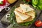 Pressed and toasted double sandwich with fresh vegetables and cheese, served with lettuce leaves on a cutting board