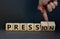 Pression to free press symbol. Businessman turns wooden cubes and changes the word pression to press. Beautiful grey table, grey