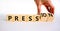 Pression to free press symbol. Businessman turns wooden cubes and changes the word pression to press. Beautiful white table, white