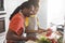 Preteen Black Girl Making Vegetable Salad While Cooking With Father In Kitchen