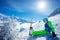 Preteen boy with alpine ski sit in snow over mountain peaks